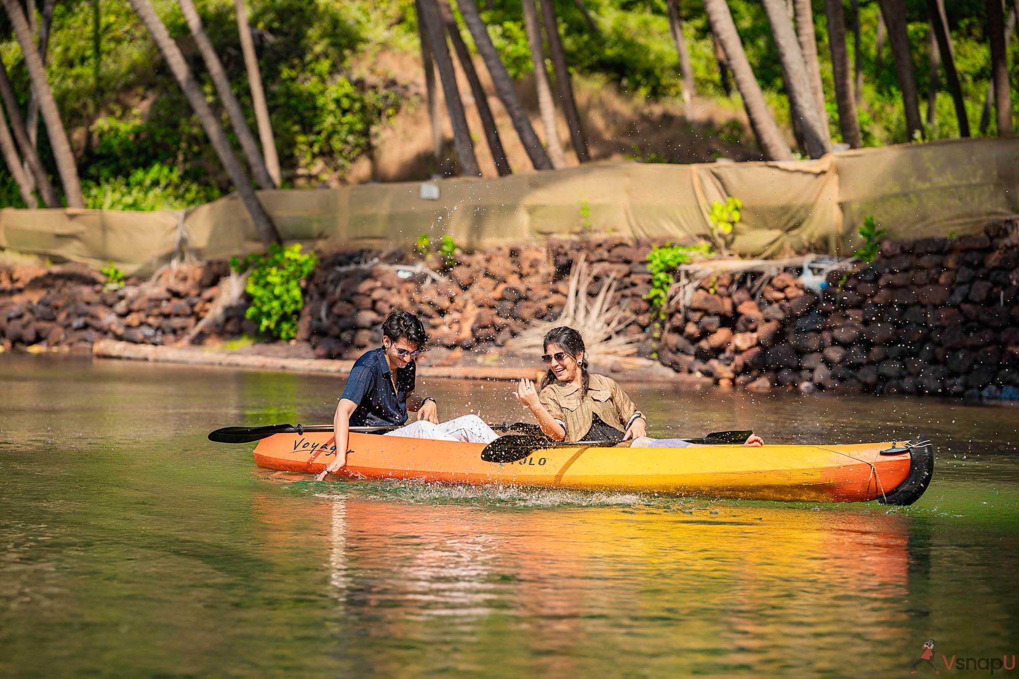 Couple in boat laughing and splashing in scenic couple photoshoot